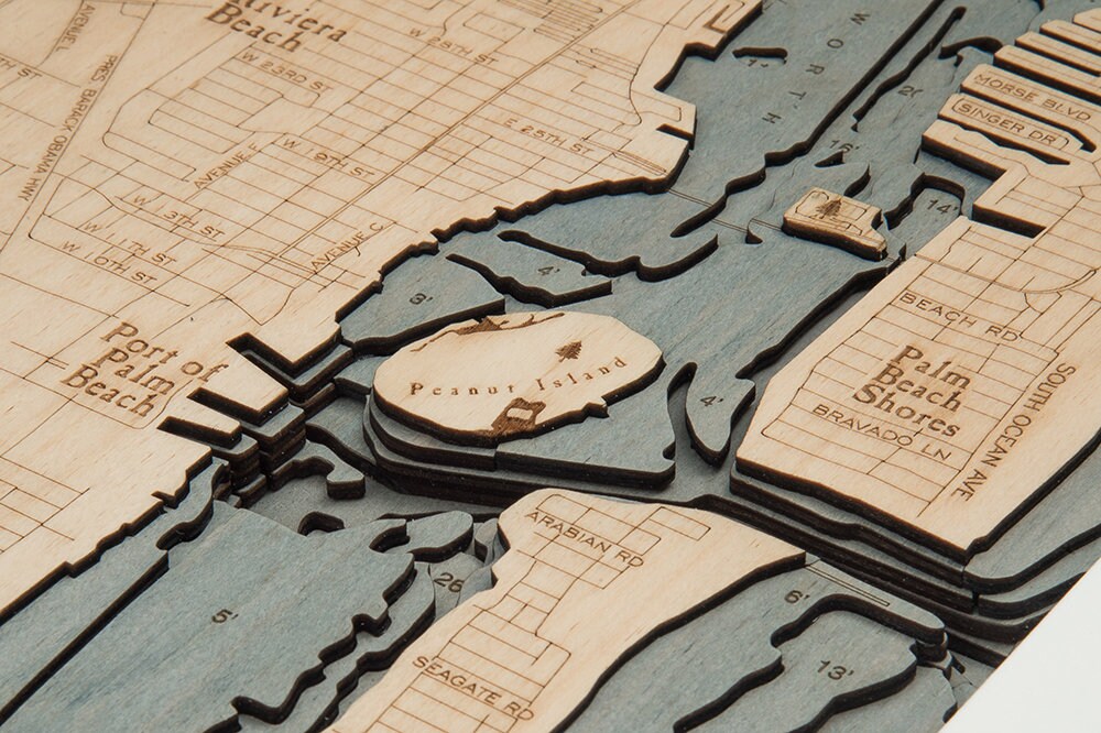 Juno Beach, Florida 3D layered wood map in laser-cut Baltic birch, shown framed against a light wall