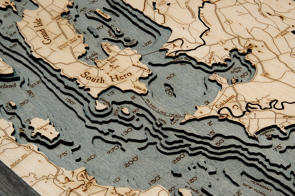 Lake Champlain 3D layered wood map in laser-cut Baltic birch, shown framed against a light wall
