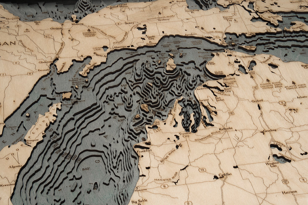 Lake Michigan 3D layered wood map in laser-cut Baltic birch, shown framed against a light wall