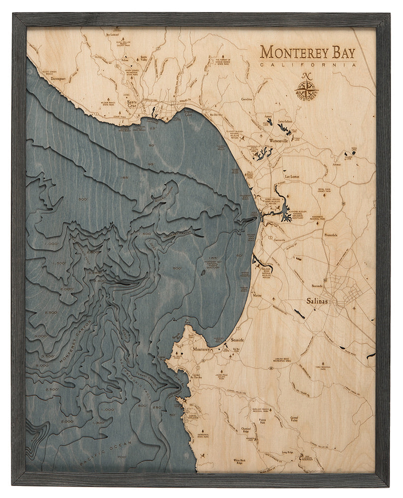 Monterey Bay, California 3D layered wood map in laser-cut Baltic birch, shown framed against a light wall
